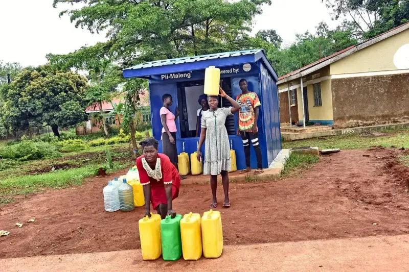 Women collecting water in yellow jerrycans at a Pii-Maleng kiosk
